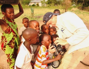 International volunteer showing a group of excited children a photo on his camera.