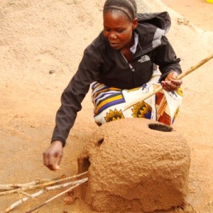 Woman working with alternative cooking technologies, rocket stove.